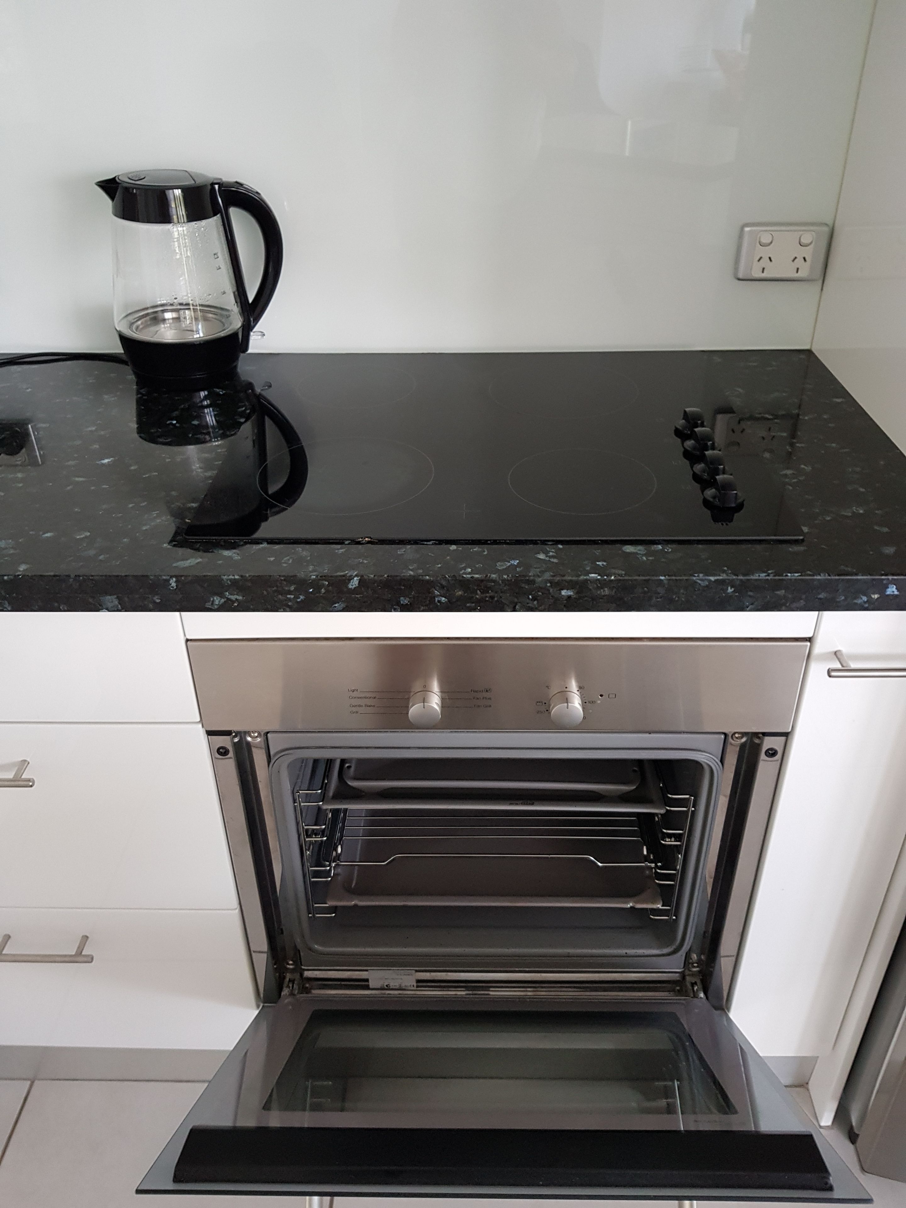 A kitchen with a black countertop, an oven, and a coffee maker.