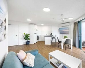 A modern living room with a sofa, a coffee table, and a dining area with chairs.