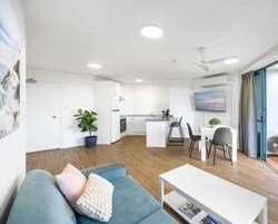A modern living room with a sofa, a coffee table, and a dining area with chairs.