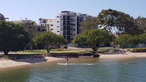 Um hotel à beira-mar, com uma praia arenosa, árvores e vista clara para o mar.