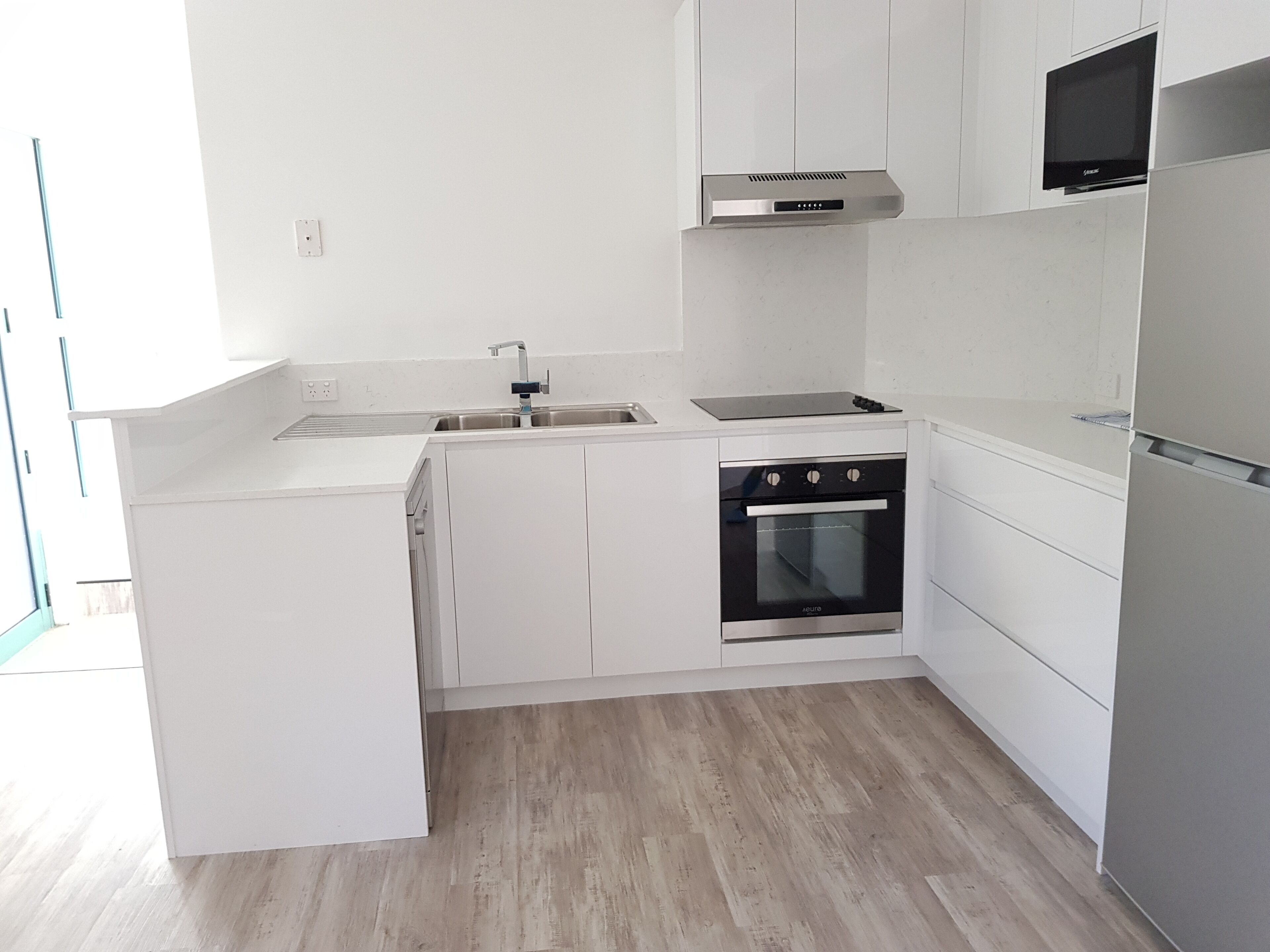 Una cocina moderna con armarios blancos, un horno de acero inoxidable y un microondas integrado.