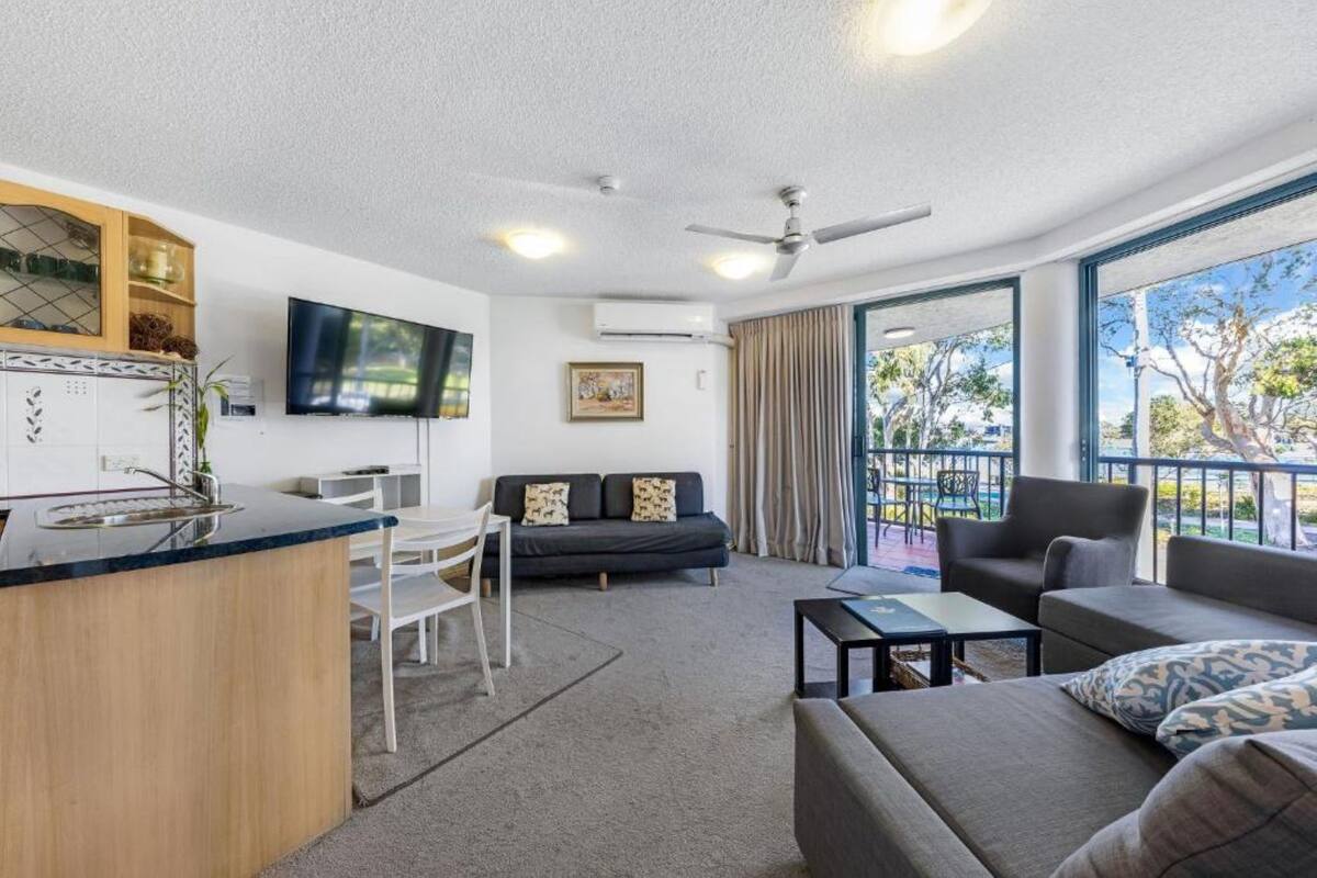 A modern living room with a kitchen area, a dining table, and a sofa.