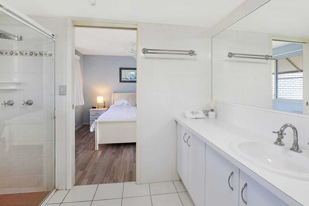 A modern bathroom with a large mirror, white cabinets, and a shower area.