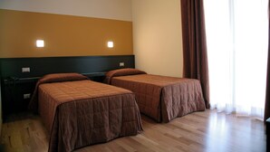 Quarto com duas camas de solteiro, teto de madeira, mesa de cabeceira com abajur e janela com cortinas.