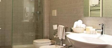 Un baño moderno con cabina de ducha de vidrio, inodoro, lavamanos y un espejo grande.