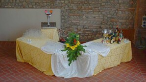 Uma mesa posta com toalhas brancas, um vaso de flores e garrafas de bebidas.