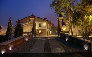A stone building with a tiled roof, a central entrance, and a pathway leading to it.
