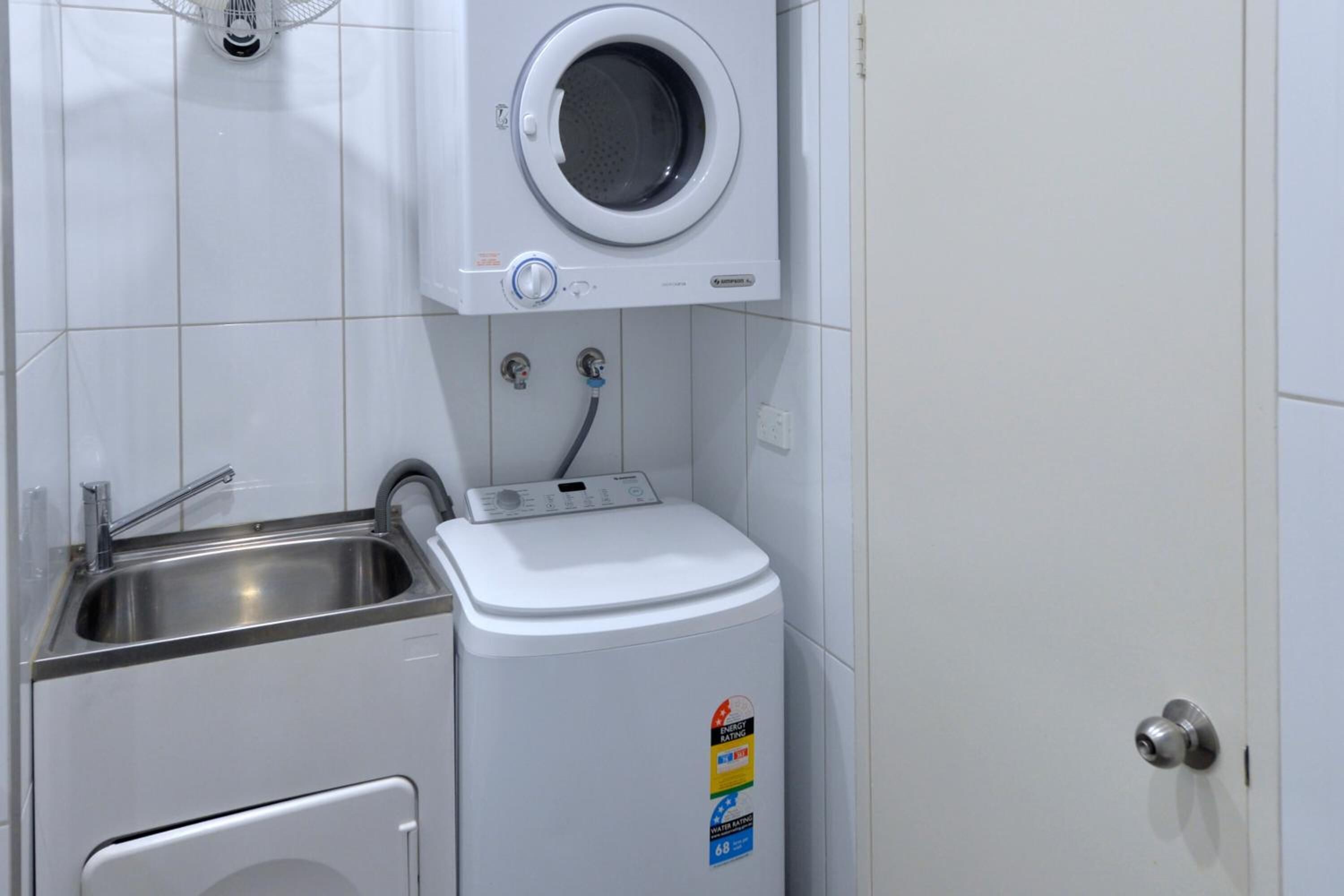 A compact laundry room with a washing machine, a sink, and a small cabinet.