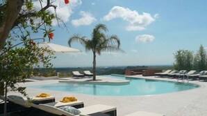 A pool area with lounge chairs and a palm tree, surrounded by a clear sky. - Torre Fiore Hotel Masseria (Pisticci)