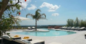 Een buitenzwembad, parasols bij het zwembad en ligstoelen