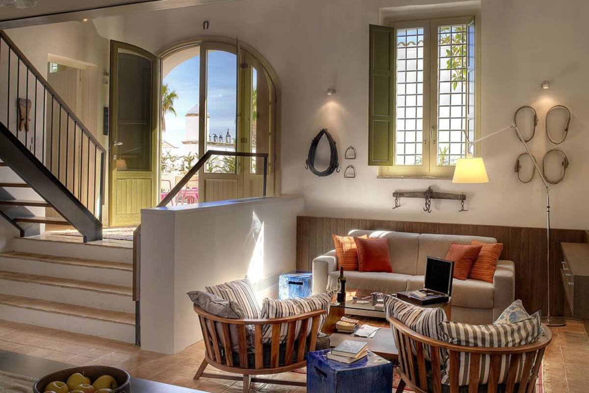 Un salón amplio con una escalera, un conjunto de sofás y una mesa de centro.