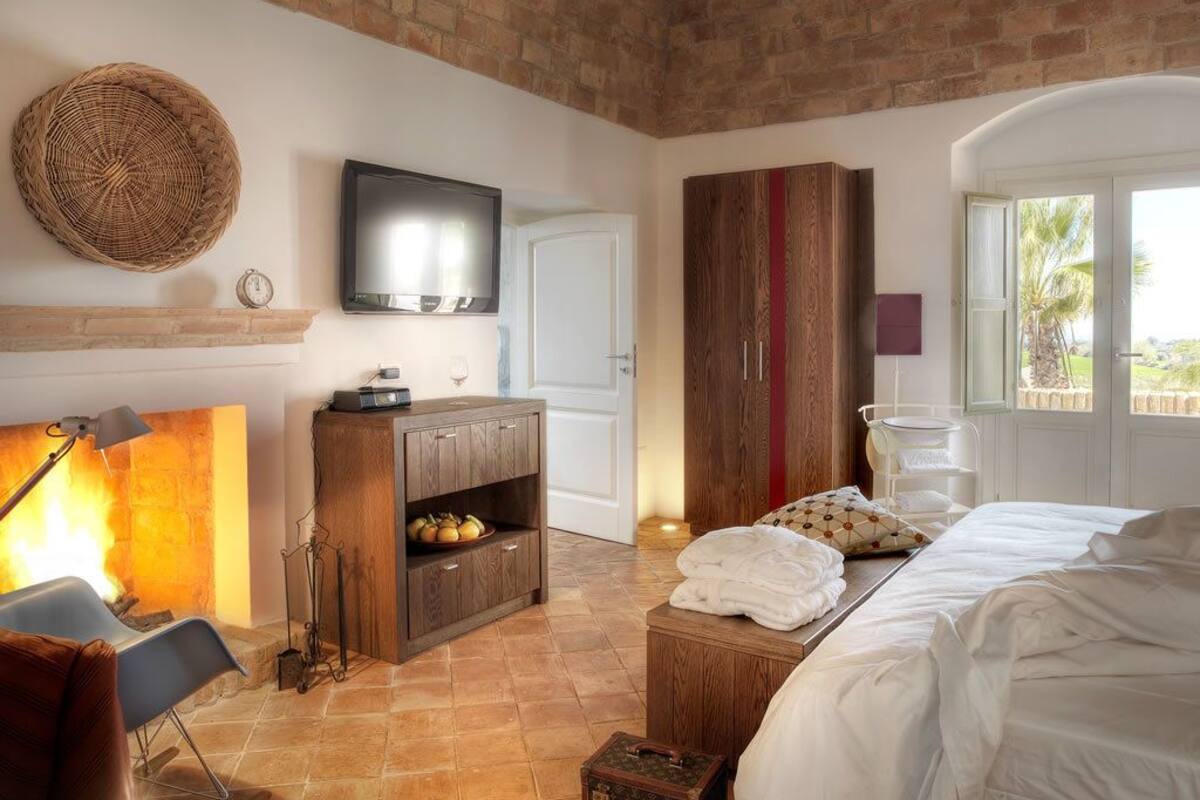Un dormitorio con techo de ladrillo, televisor, armario, cama y ventana con vistas.
