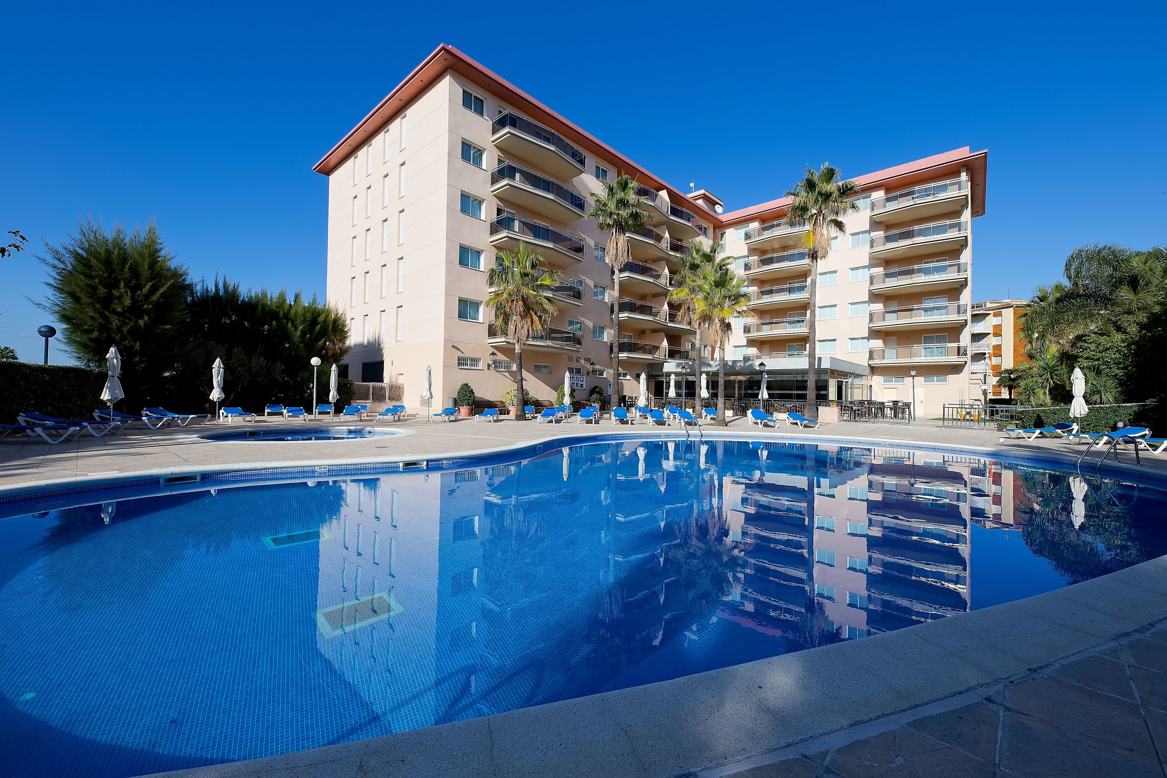 Una piscina al aire libre, sombrillas, tumbonas