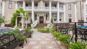 A grand building with a central staircase, multiple balconies, and a well-maintained garden area. - Villa Venezia (Odesa)