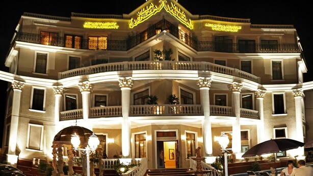 A multi-story building with a grand entrance, balconies, and a sign indicating it is an apartment restaurant. - Villa Venezia (Odesa)