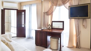 A hotel room with a large bed, a desk with a television, and a view of the outside through large windows. - Villa Venezia (Odesa)