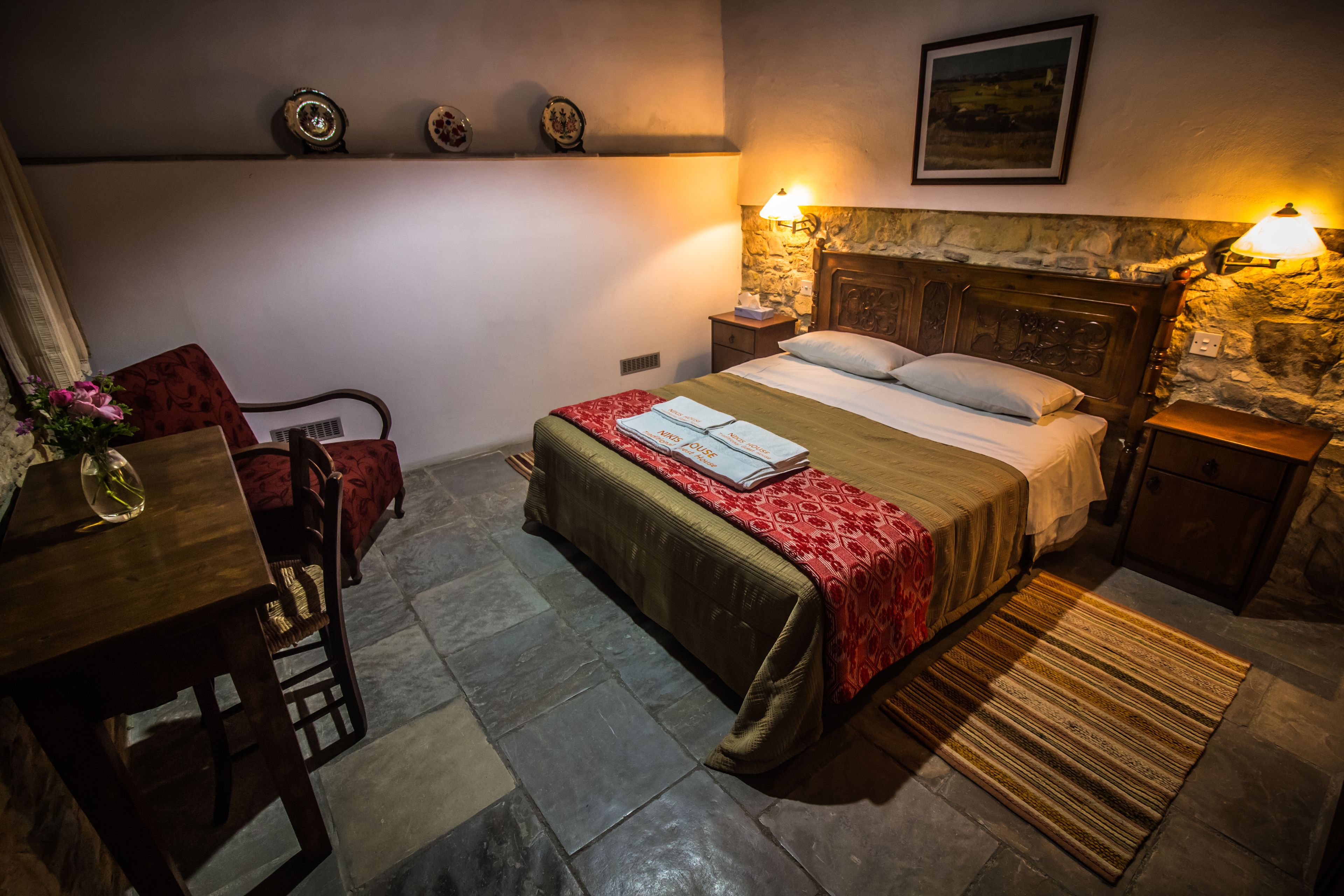 Een slaapkamer met een bed, nachtkastjes, een bureau en een stoel.