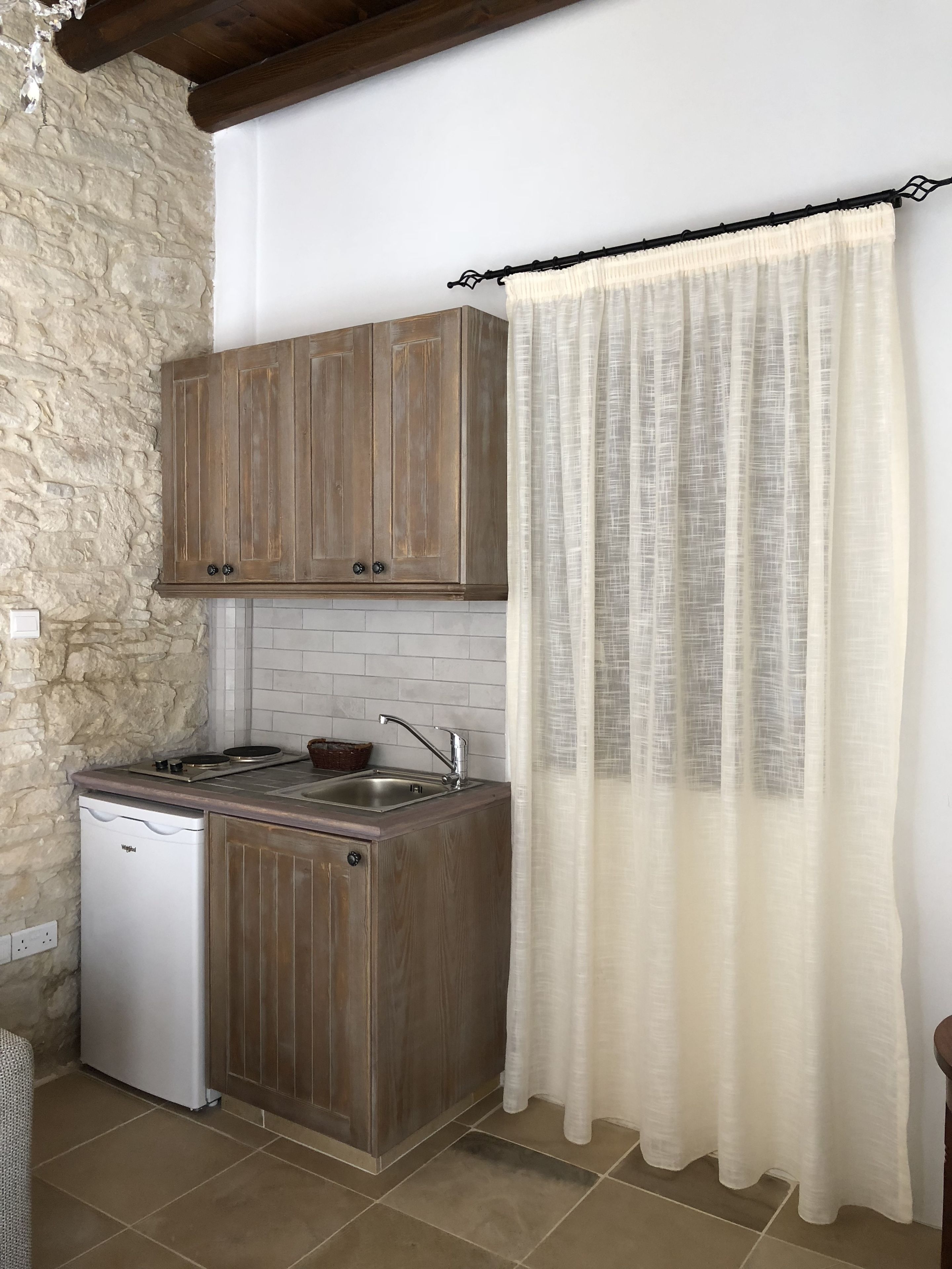 A compact kitchen with wooden cabinets, a built-in dishwasher, and a tiled backsplash.