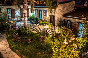 Edificio de piedra con un patio que ofrece mobiliario exterior y abundante vegetación.