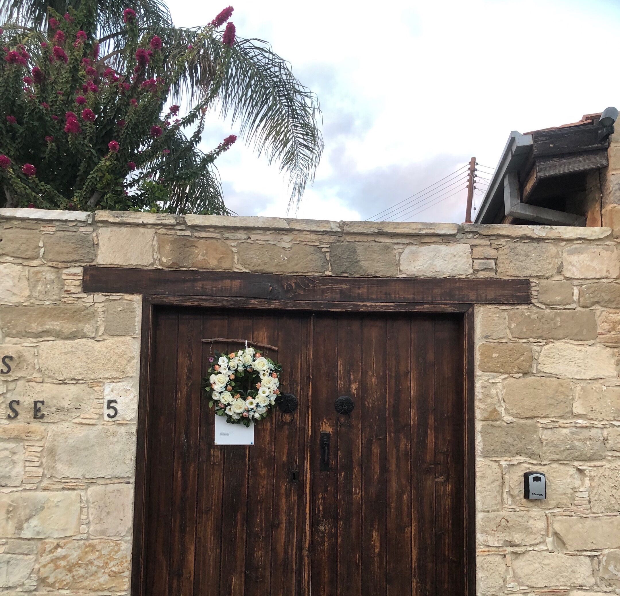 A stone wall with a wooden door, a wreath, and a small plaque.