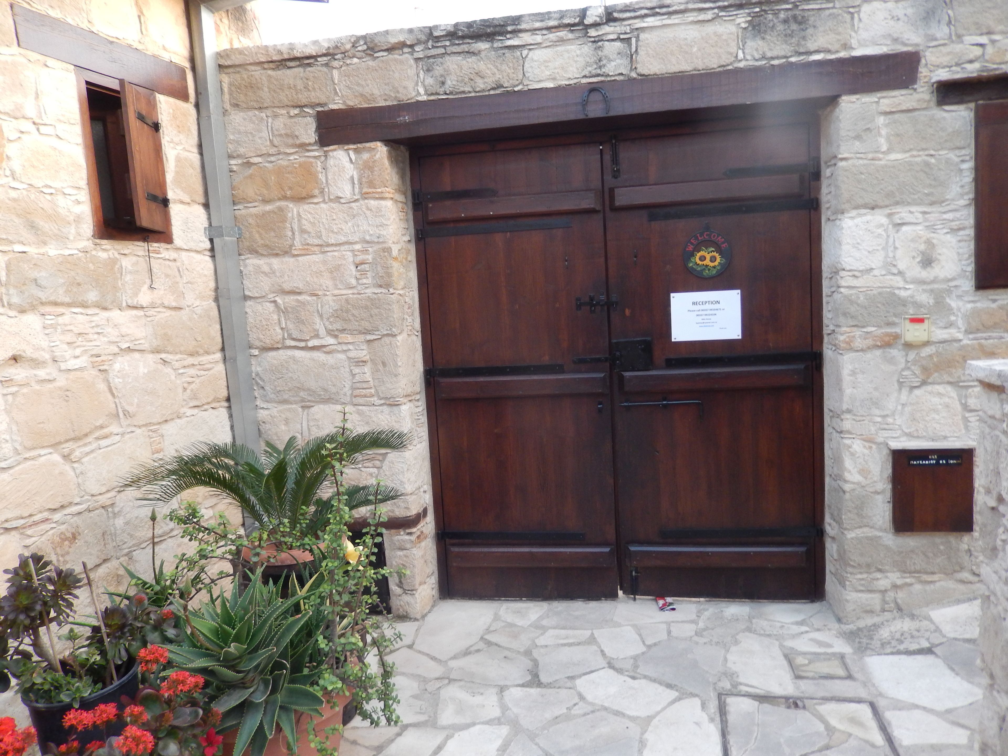 A stone building with a wooden double door, a reception sign, and potted plants.