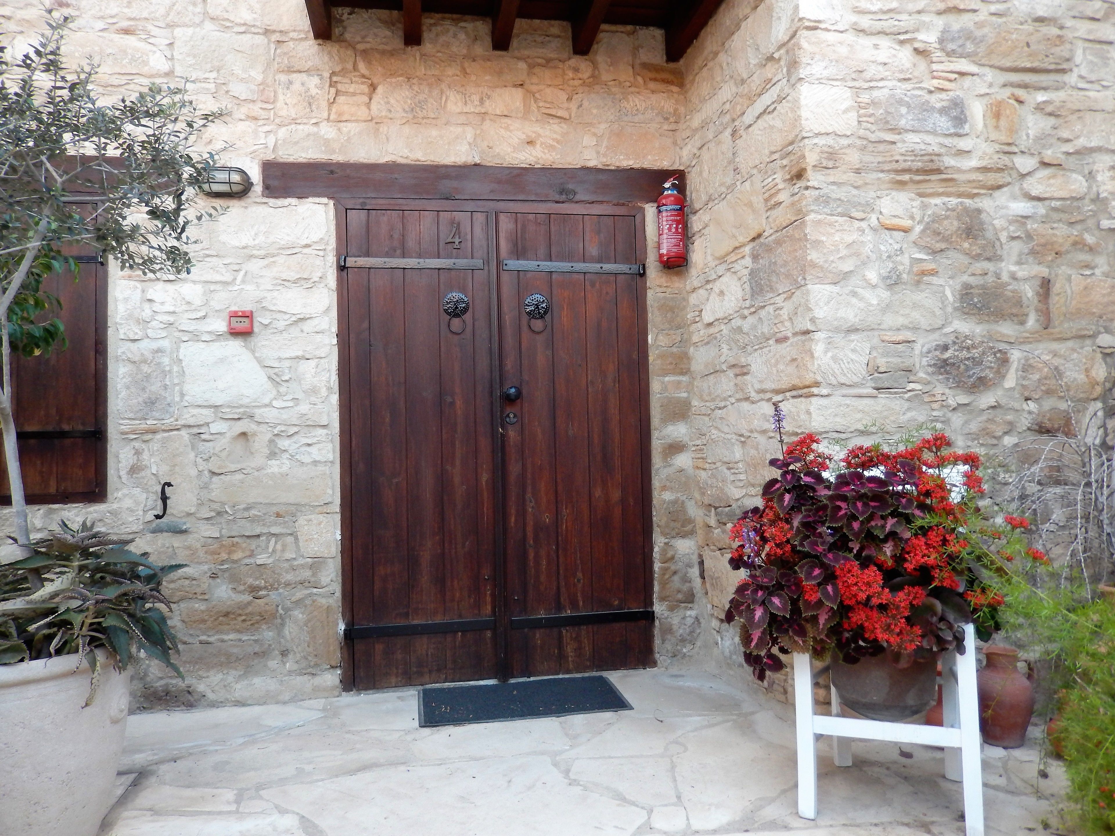 A stone building with a wooden double door, a fire extinguisher, and potted plants.