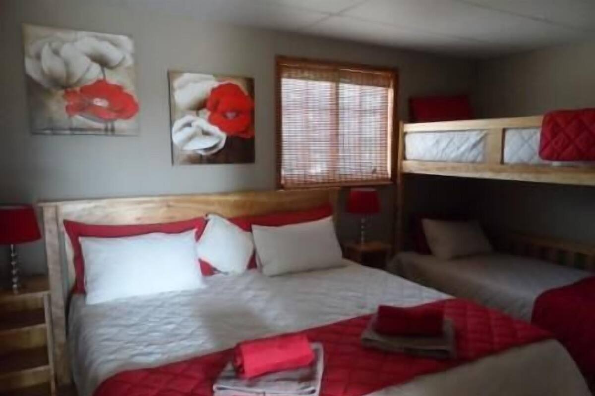 A room with a wooden bed, two bedside tables, and a window with blinds.