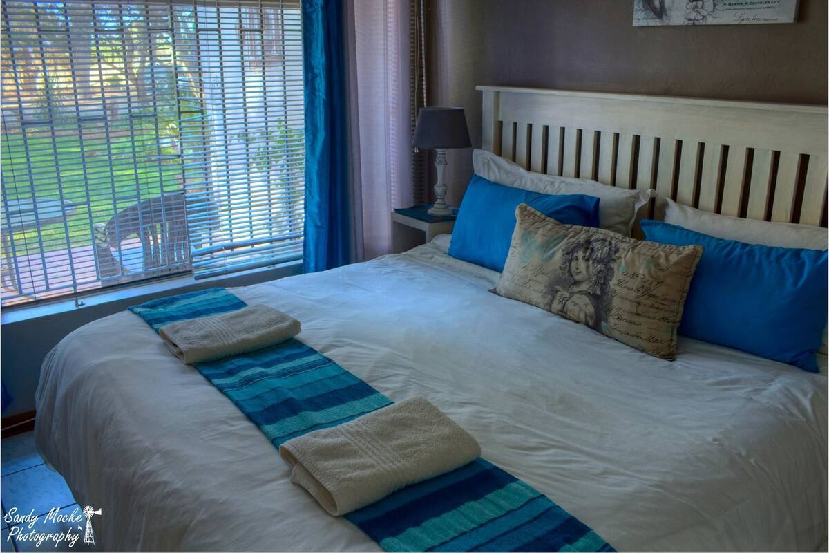A neatly made bed with a striped blanket, a headboard, and pillows with a vintage design.