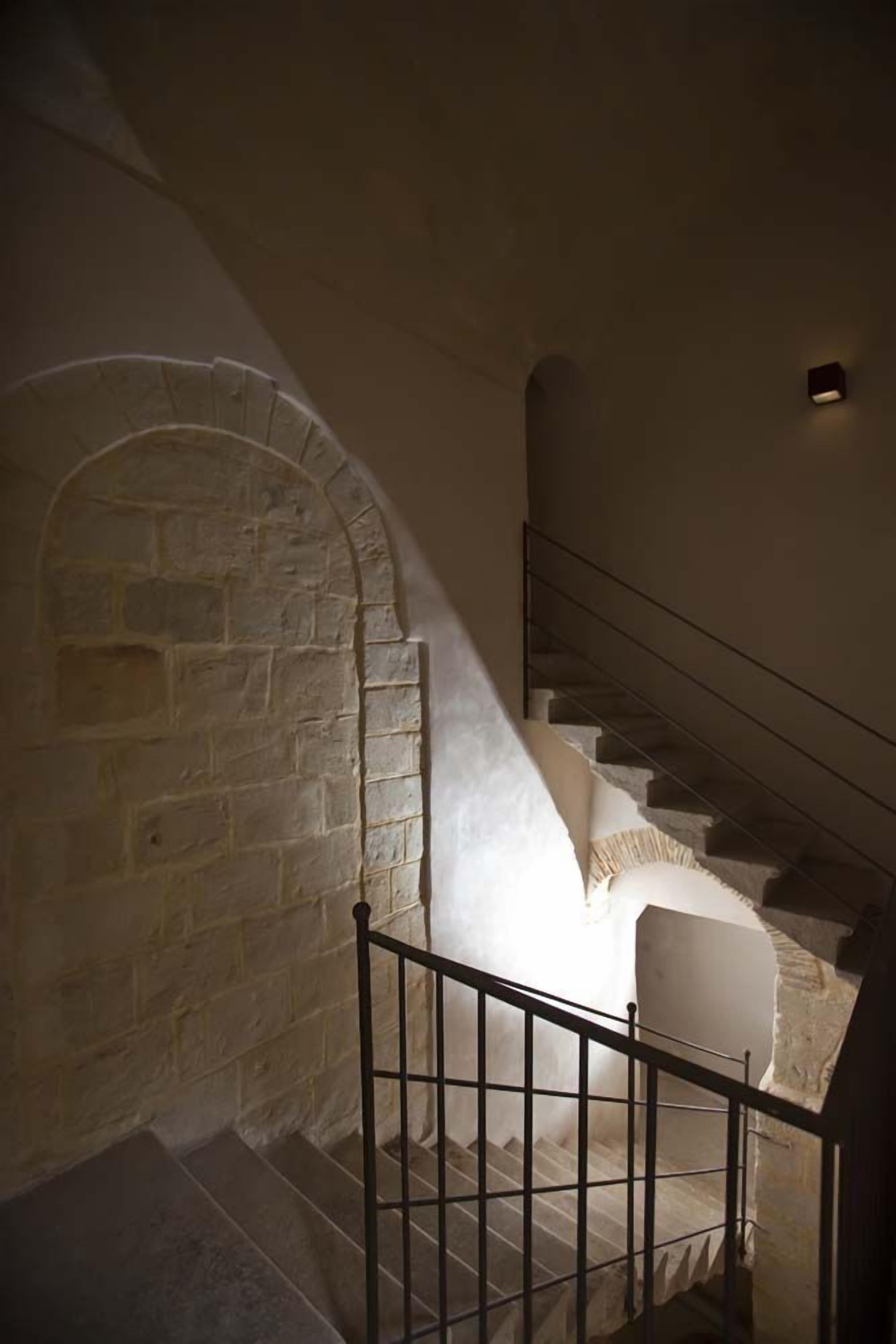 Un escalier avec un mur en pierre d’un côté et une rampe en métal de l’autre.