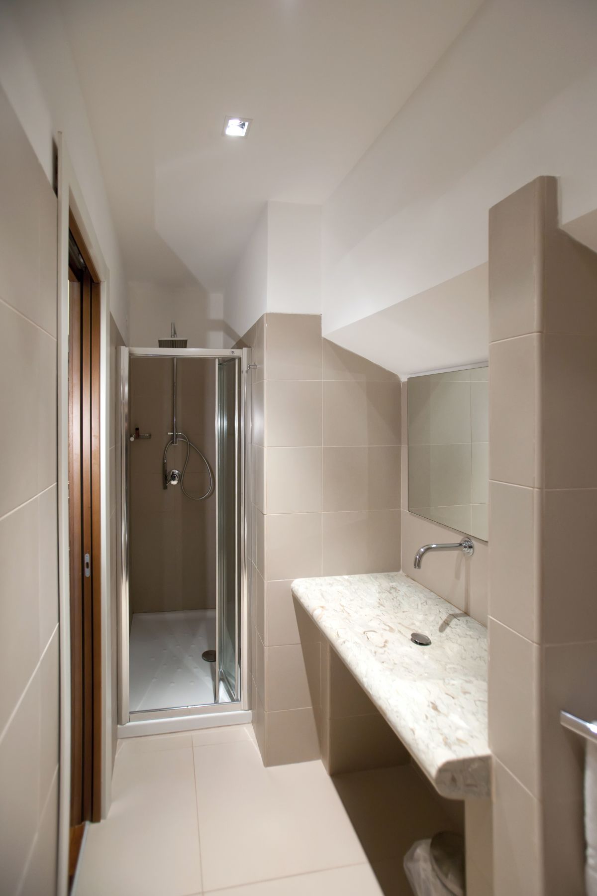 A modern bathroom with a glass-enclosed shower, a marble countertop, and a large mirror.