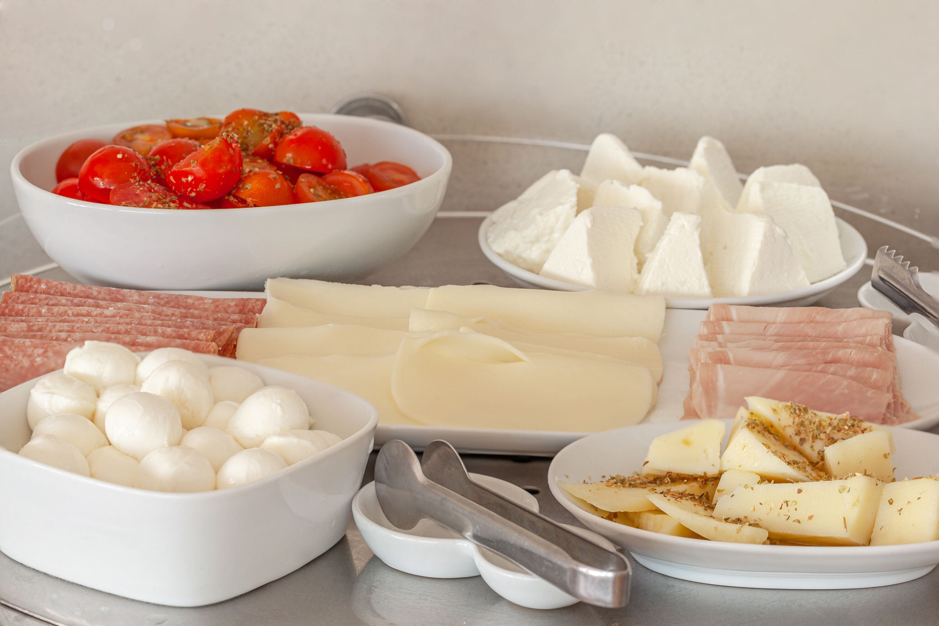 Una selezione di formaggi, salumi e pomodori su un tavolo.