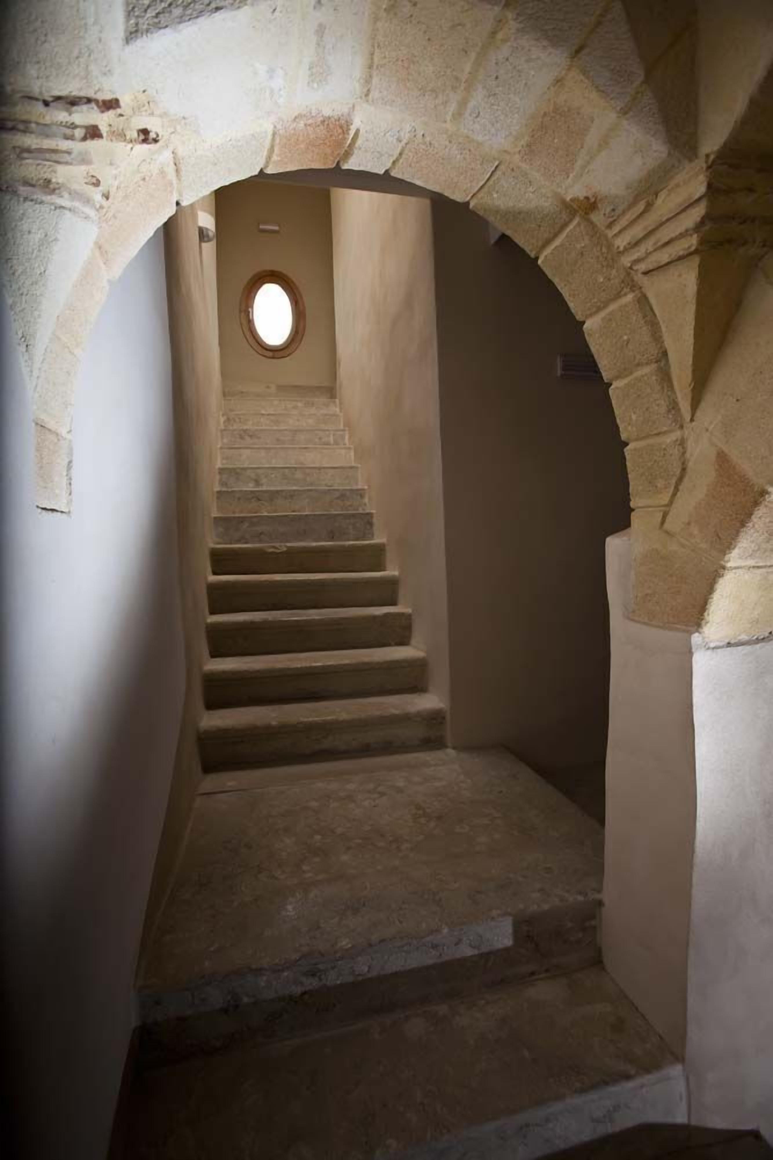 A stone staircase leading upwards, with a circular window at the top.