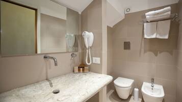 A bathroom with a marble sink, a toilet, a bidet, and a hairdryer mounted on the wall.