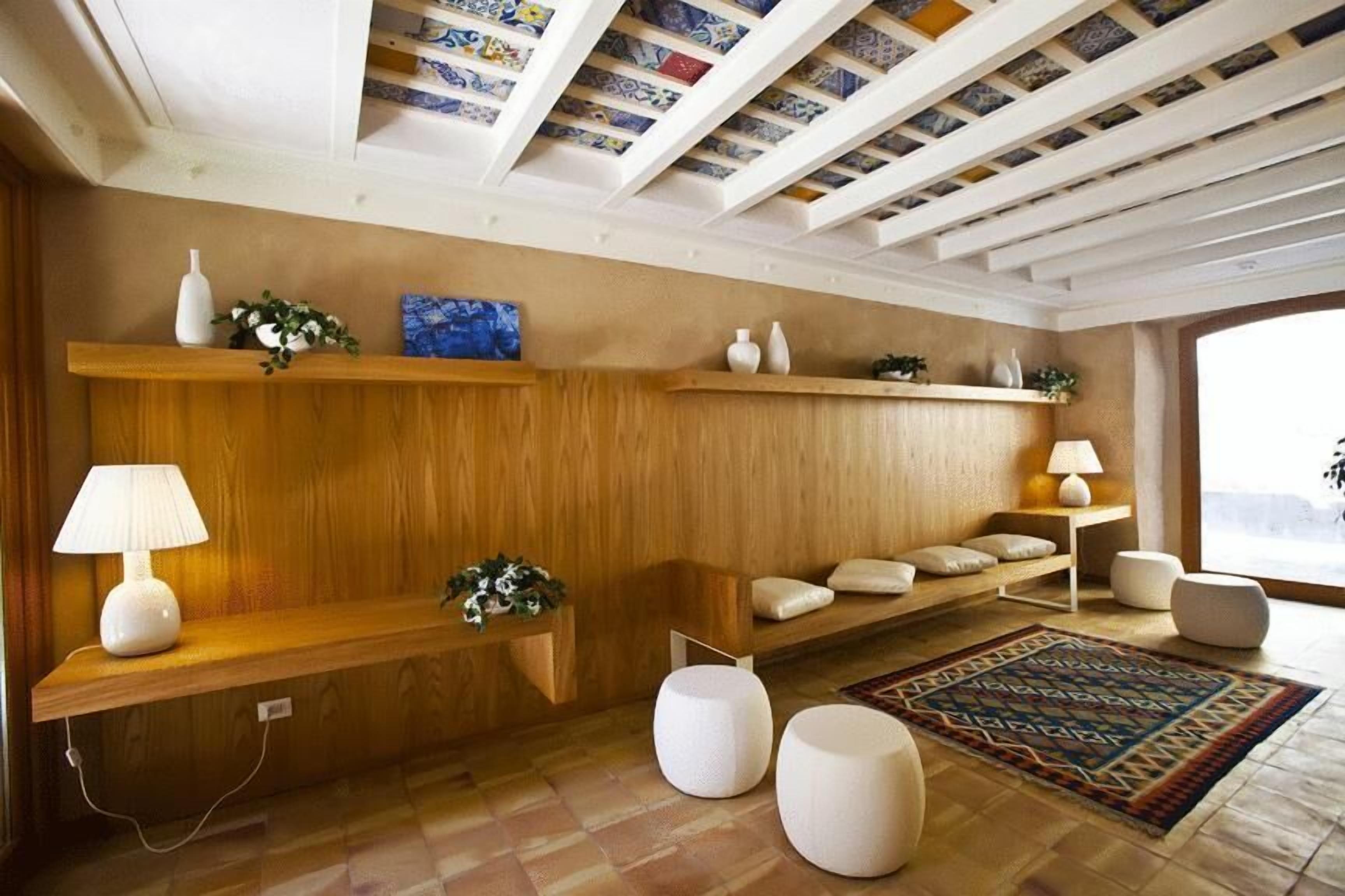 A modern living room with wooden paneling, a patterned rug, and a ceiling with exposed beams and tiles.