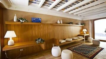 A modern living room with wooden paneling, a patterned rug, and a ceiling with exposed beams and tiles.
