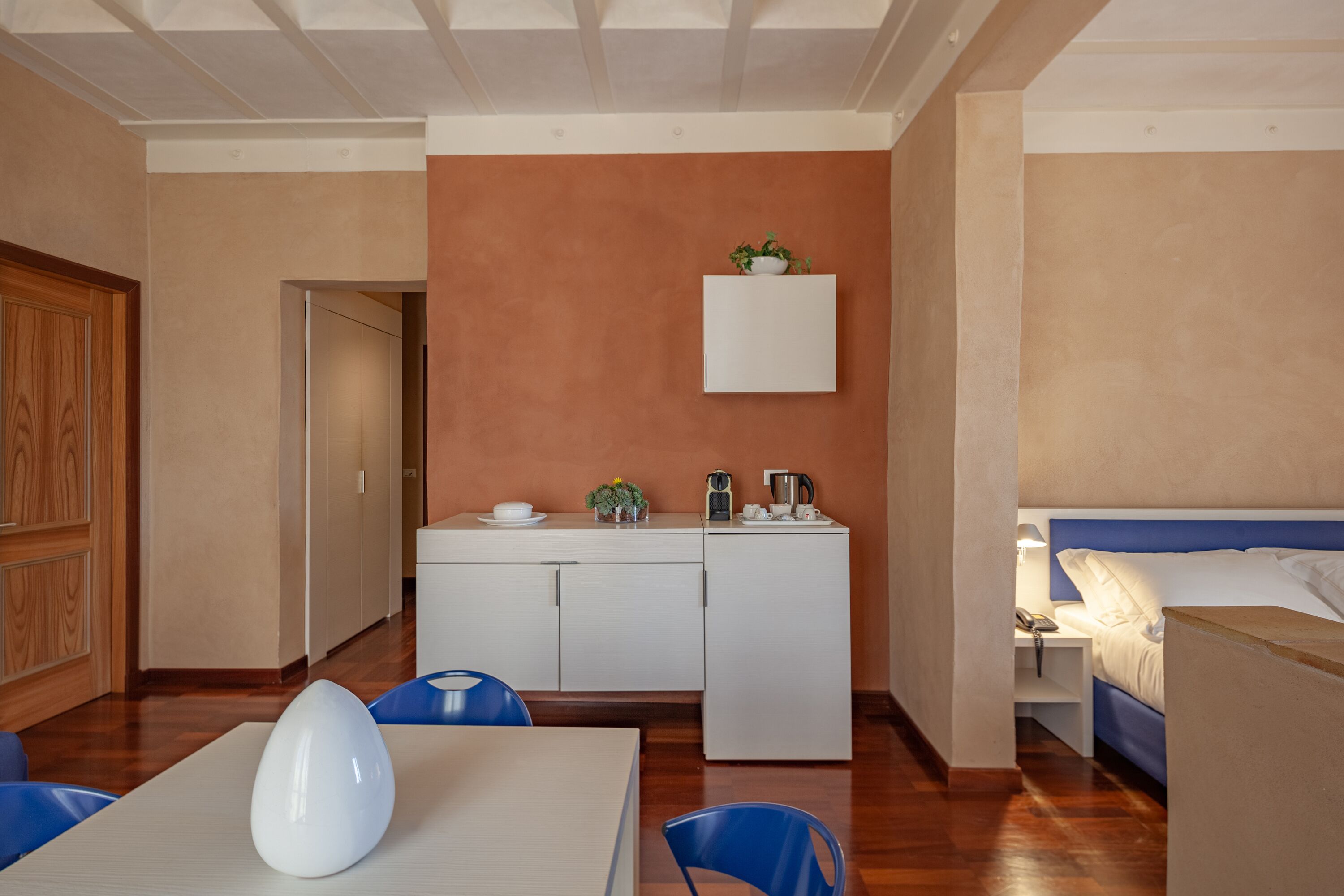 Habitación de hotel compacta con kitchenette, zona de comedor y cama.