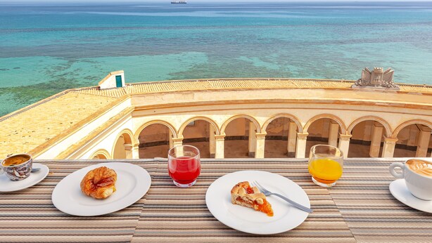 A table with breakfast items and a view of the sea. - Residence La Gancia (Trapani)