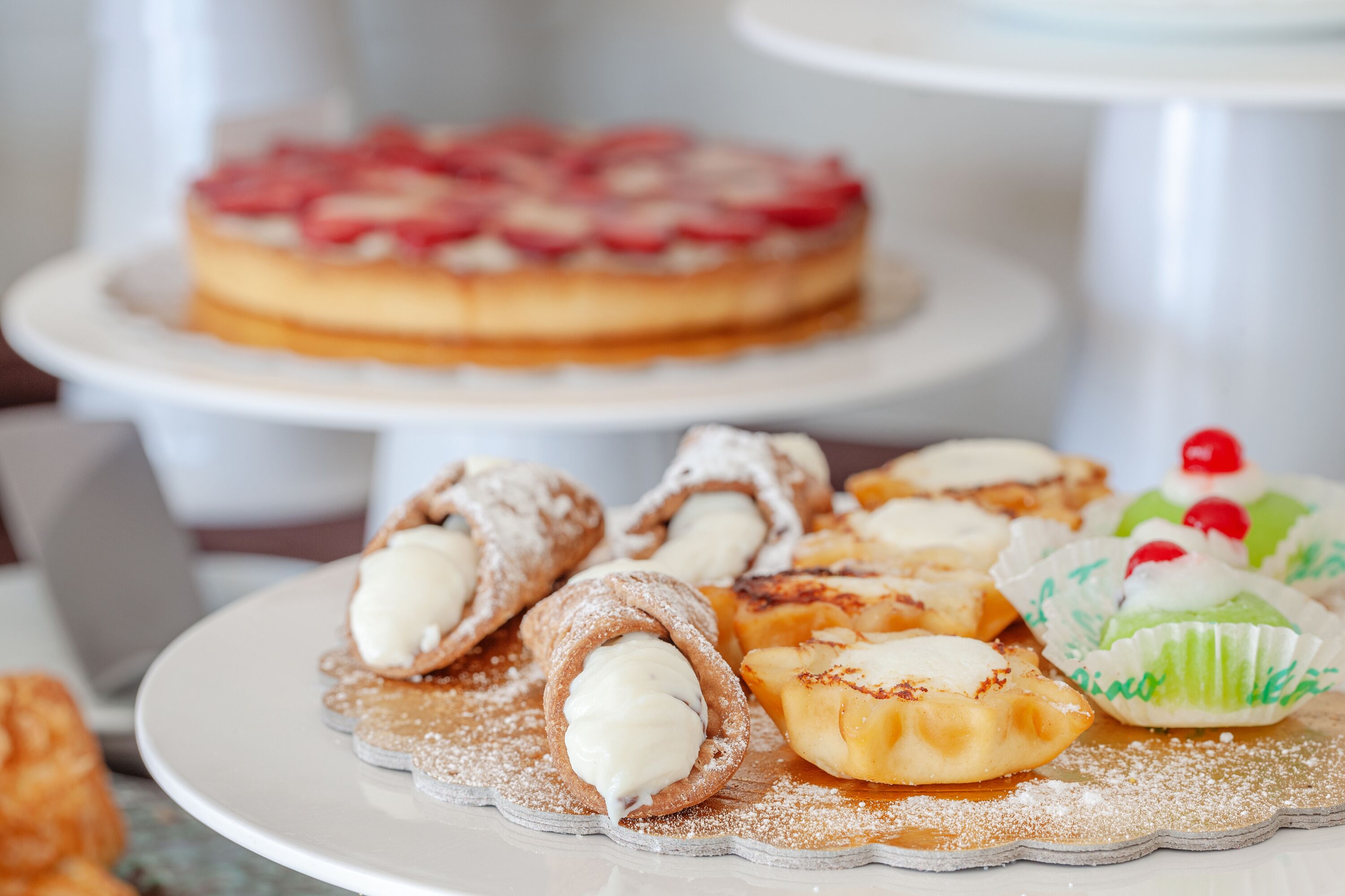 A variety of desserts on a white plate, including a cake with strawberries on top.