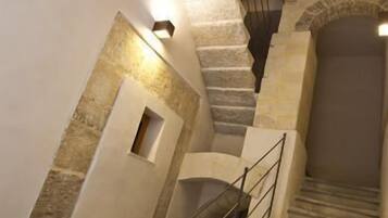 Un escalier en pierre avec une rampe métallique, menant à un niveau supérieur.