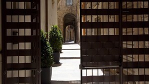 A view through a wooden gate into a building with arched passageways and potted plants. - Residence La Gancia (Trapani)