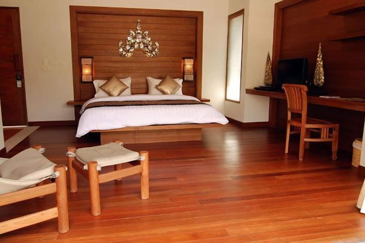 Un dormitorio con cabecera de madera, una cama con ropa blanca, una silla de madera y un escritorio con silla.