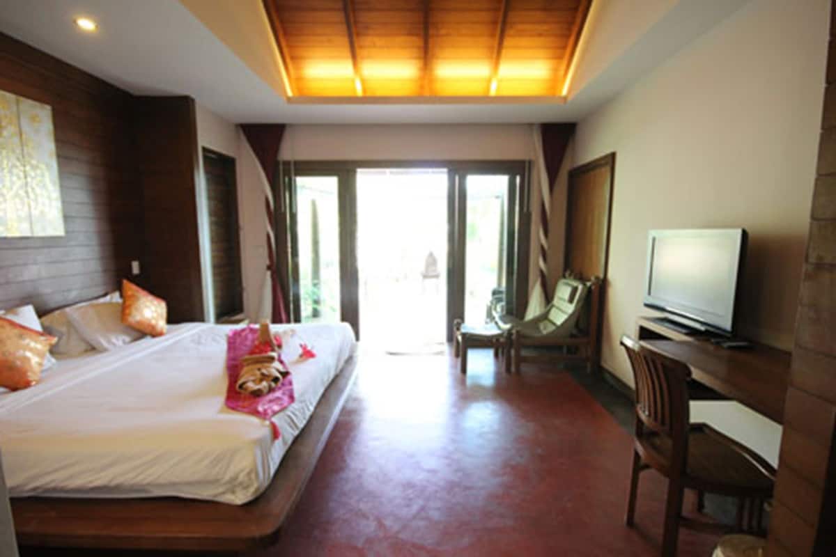 Habitación de hotel con una cama grande, televisión, escritorio y silla.