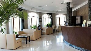 Un hall d’entrée spacieux, doté d’un comptoir de réception, de sièges confortables et de grandes fenêtres laissant entrer la lumière naturelle.