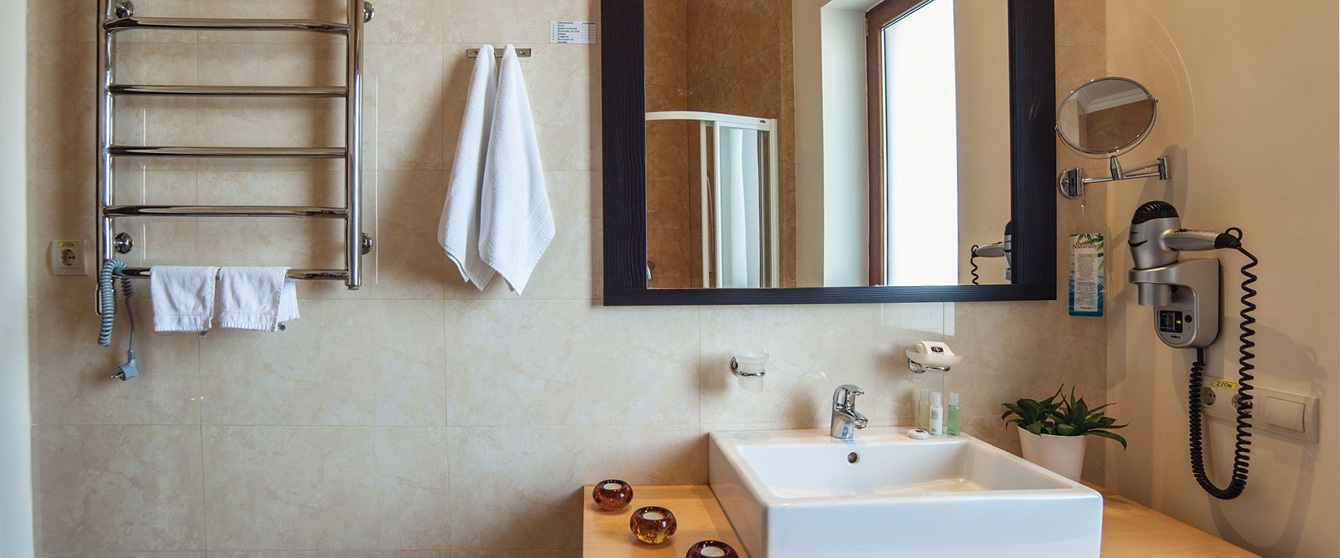 A modern bathroom with a built-in towel rack, a large mirror, a hairdryer, and a sink.