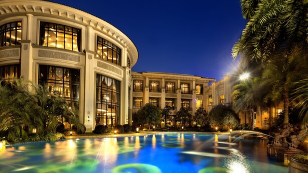Un grand hôtel, bien éclairé, doté d’une piscine dont les motifs sont illuminés.