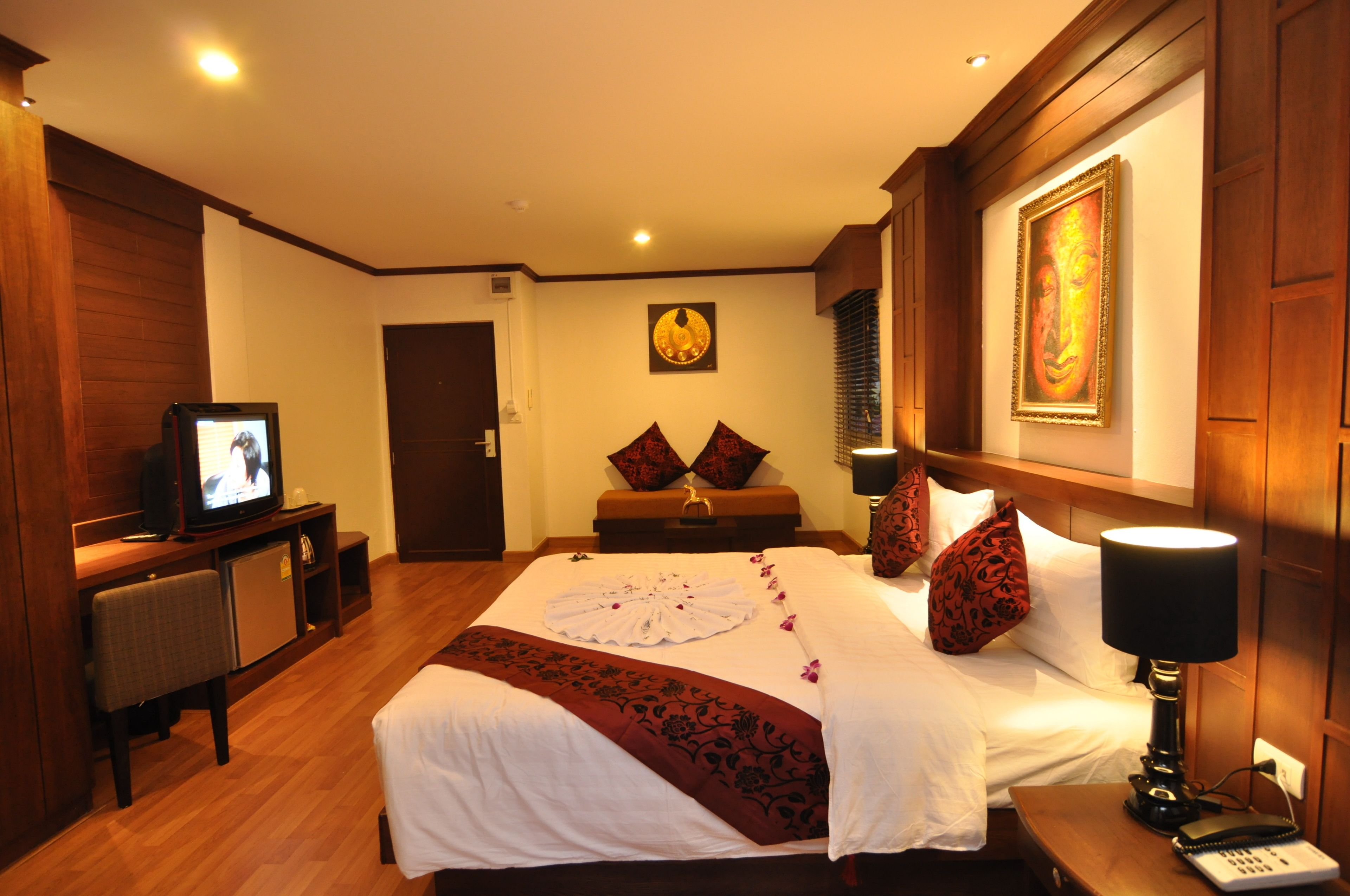 Una habitación de hotel con cama, televisión, escritorio y mesita de noche.