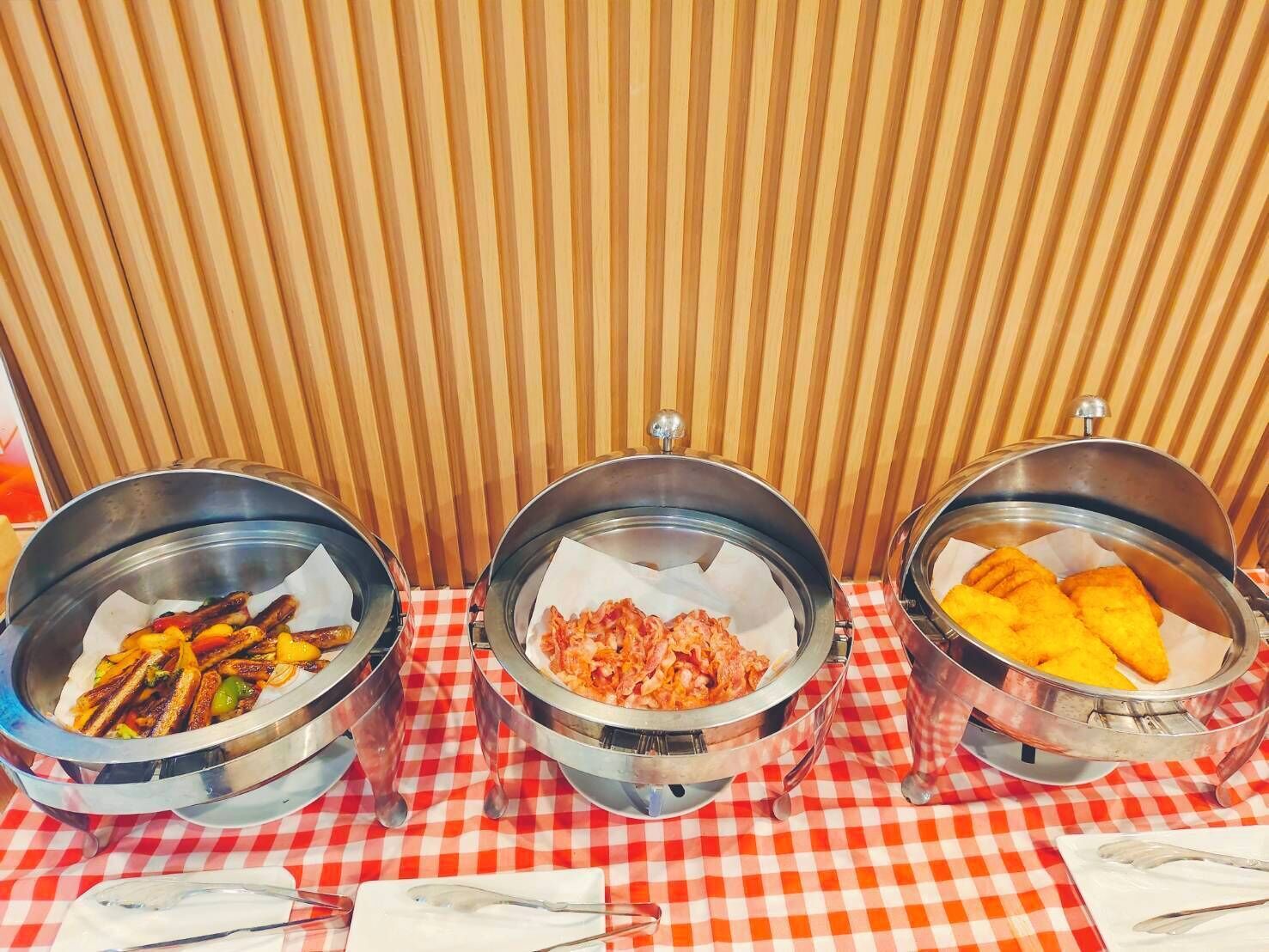 Three metal bowls with food on a checkered tablecloth.