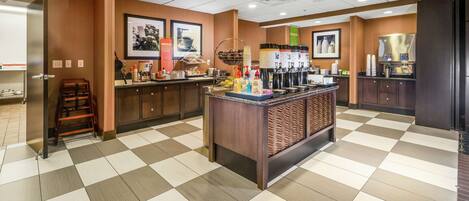 A hotel lobby with a checkered floor, a reception desk, and a coffee station.
