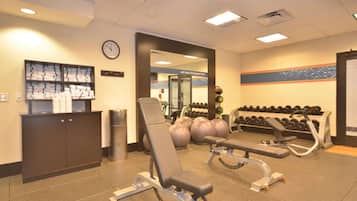 A gym with exercise equipment, a clock, and a wall with a decorative border.