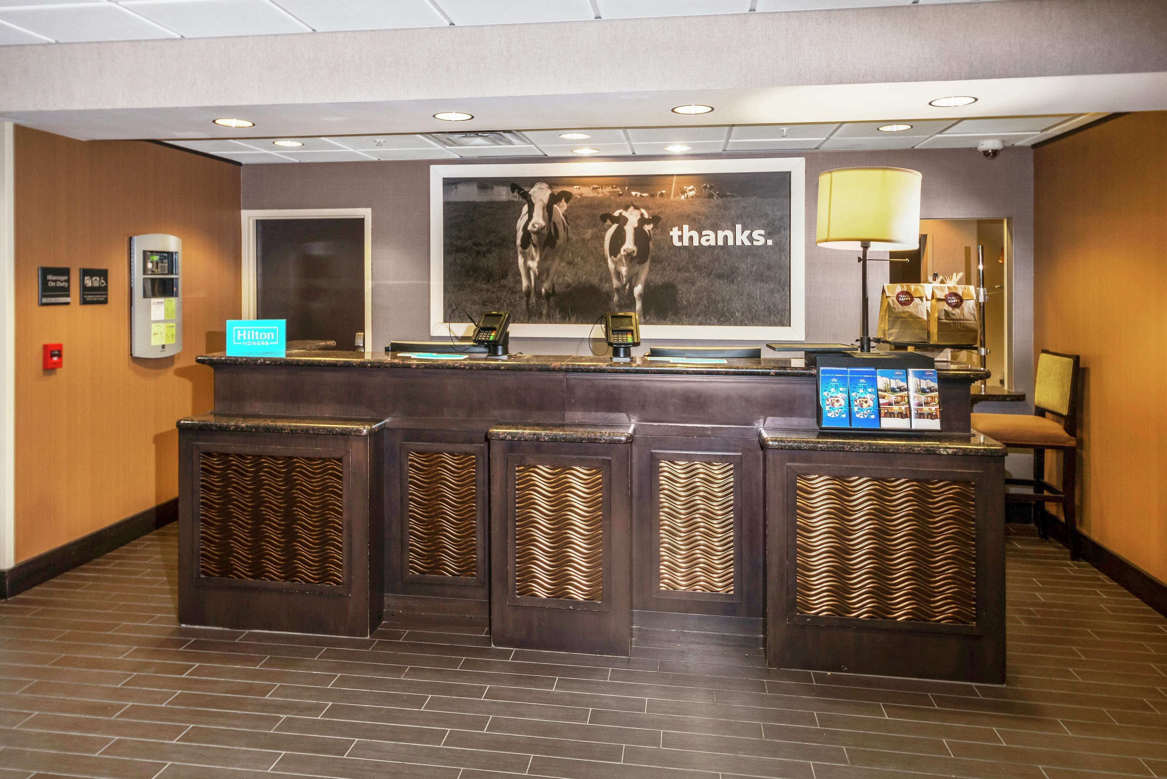 Un mostrador de recepción de hotel con un cartel grande que dice 'gracias', un quiosco digital y una lámpara.